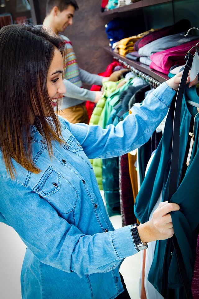 Female & male shopper looking through items of clothing on a rail 